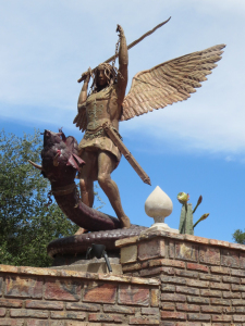 A statue of San Miguel slaying a serpent adorns the entry wall.